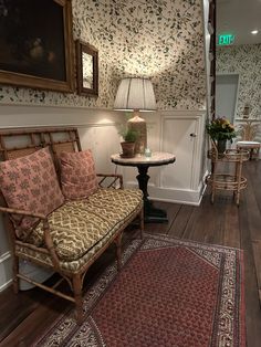 a living room filled with furniture next to a table and lamp on top of a wooden floor