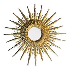 a mirror that is sitting on top of a white surface and has gold colored sticks in the shape of a sunburst