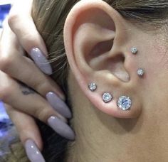 a woman's ear with three different piercings