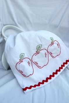 an embroidered apple pillow on a white bed