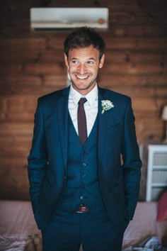 a man in a suit and tie standing next to a wall with wood paneling