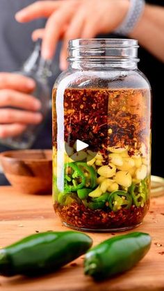 a jar filled with spices sitting on top of a wooden table next to green peppers