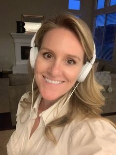 a woman wearing headphones and smiling at the camera in front of a living room