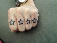 a person's hand with three stars tattooed on it