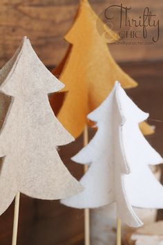 three paper trees sitting on top of a table next to each other, one is white and the other is brown