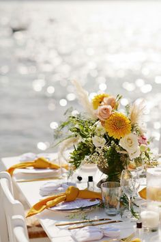 the table is set with yellow and white flowers