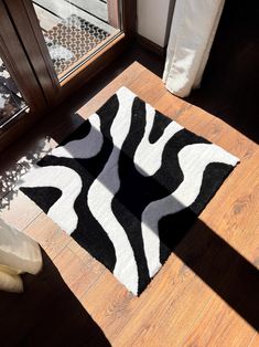 a black and white rug sitting on top of a wooden floor next to a window