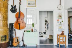 a living room with guitars hanging on the wall and other musical instruments in front of it