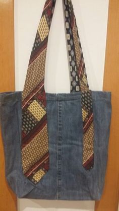 a denim bag hanging on the wall with a tie around it's neck and bottom