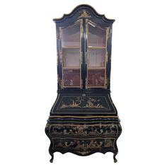 an old fashioned black and gold desk with glass doors on the top, sitting against a white background