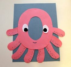 an octopus made out of construction paper on a white wall with eyes and nose drawn onto it