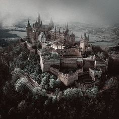 an aerial view of a castle in the middle of trees and land, with dark clouds overhead