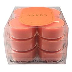 six candles in a clear box with an orange label on the top and bottom that says sands see bottom panel for safety information