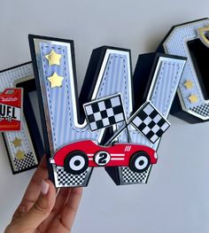 a hand holding up some paper cars on top of each other with the letter n