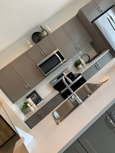 a modern kitchen with stainless steel appliances and white counter tops, along with gray cabinets