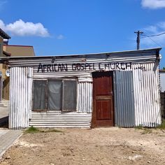 an old run down building with two doors on the front and one door open to let in light