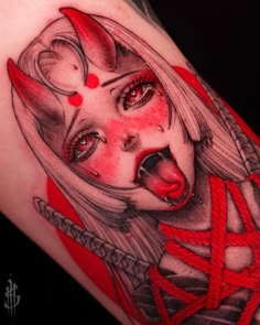 a woman's face with red eyes and horns on her arm