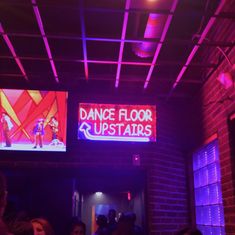 the dance floor upstairs is lit up with purple lights and people are standing in line