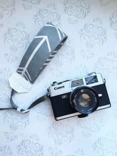 an old camera is laying on the ground next to a roll of toilet paper and a bag