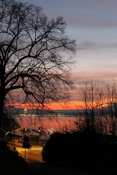 the sun is setting over some water and trees