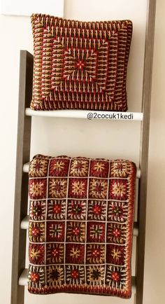 two decorative pillows sitting on top of each other in front of a wall mounted shelf