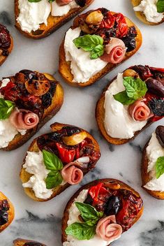 several pieces of bread with various toppings on them sitting on a marble counter top