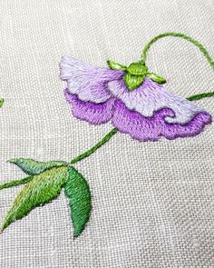 a close up of a purple flower on a white cloth