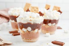 two dessert cups filled with marshmallows, chocolate pudding and graham crackers