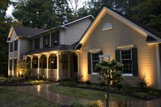 a house that is lit up with lights in the front yard and landscaping around it