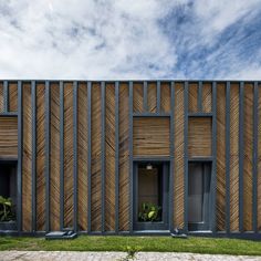 a building with wooden panels on the front and side walls, along with green grass