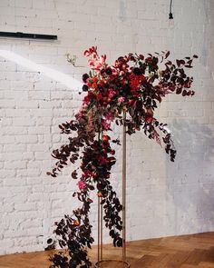 a tall metal planter filled with lots of flowers on top of a wooden floor