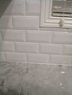 a bathroom with white tile on the walls and floor, along with an open window