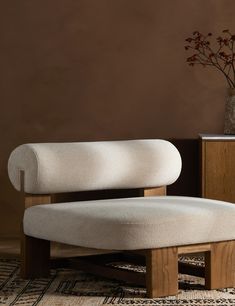 a white chair sitting on top of a rug next to a vase with flowers in it