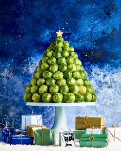 a christmas tree made out of brussels sprouts and wrapped presents on a platter