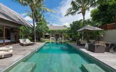 an outdoor swimming pool with lounge chairs and umbrellas next to the side of it