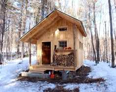 a small cabin in the woods with snow on the ground