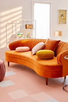 an orange couch sitting on top of a pink floor next to a chair and table