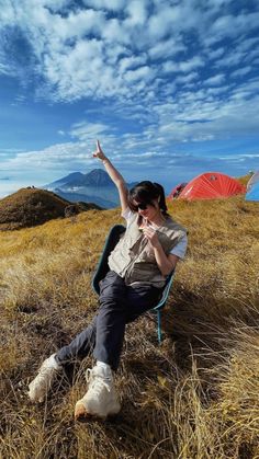 a woman sitting in a chair on top of a dry grass field