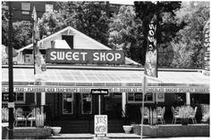 an old black and white photo of a storefront with awnings that says sweet shop