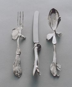 three pieces of silverware with flowers and leaves attached to each other, including a fork and knife