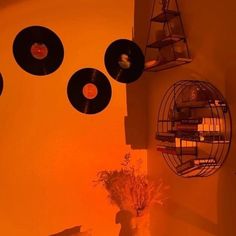 an orange room with record discs hanging from the ceiling and flowers in a vase next to it