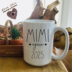 a white coffee mug sitting on top of a wooden table next to potted plants