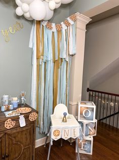 a baby's first birthday party with balloons and cookies on the table in front of it