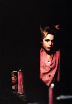 a woman leaning against a wall next to two cans