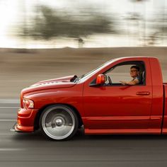 a red truck driving down a street next to tall buildings