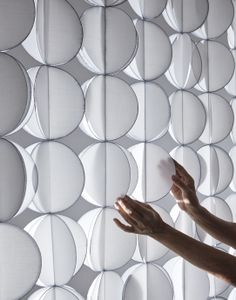 a person reaching up to touch the wall made out of circles and round holes on it