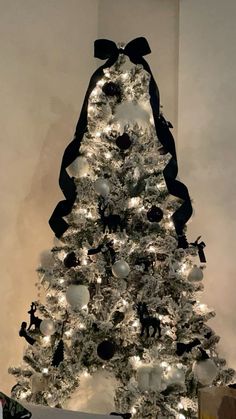 a white christmas tree with black ribbon and ornaments