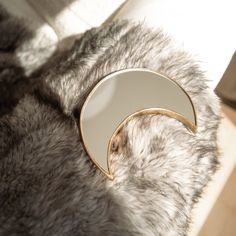 a white and gold plate sitting on top of a fur covered floor next to a window