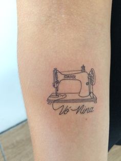 a tattoo on the arm of a woman with a sewing machine in front of her