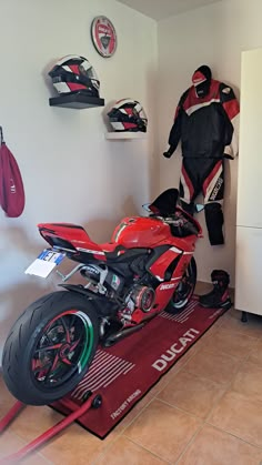 a red motorcycle parked next to a white refrigerator in a room with other items on the wall